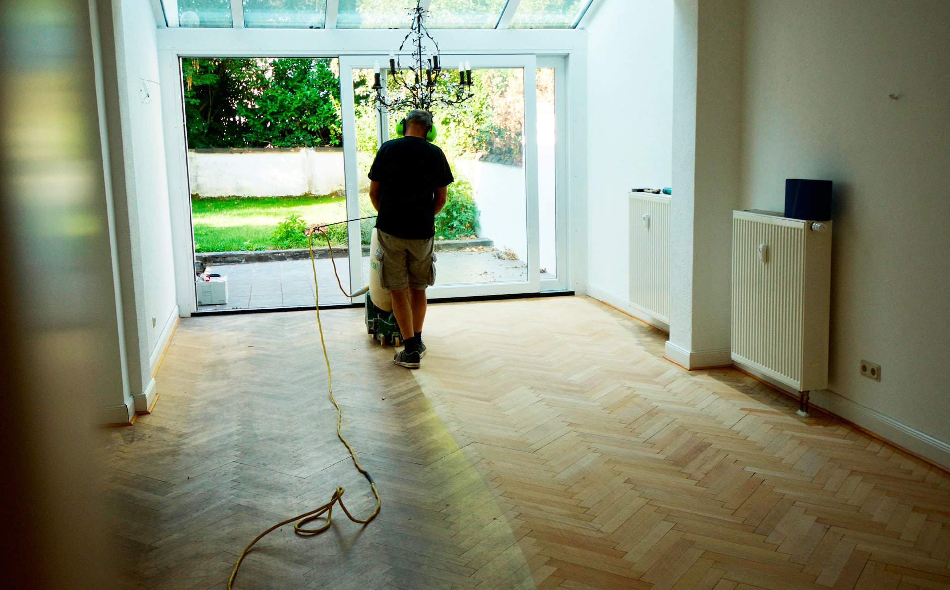 Ein Mann arbeitet an einem Holzboden in einem Raum mit Referenzen. Fussbodentechnik Schwallach -Bodenbeläge, Vinylbelag, Parkett - Neckaraue 7 - 71686 Remseck